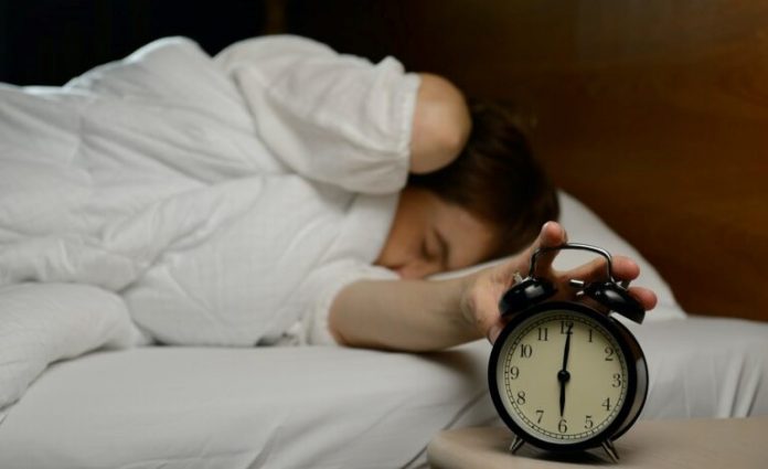 Woman Turning Off The Alarm Clock On The Bed 768x513